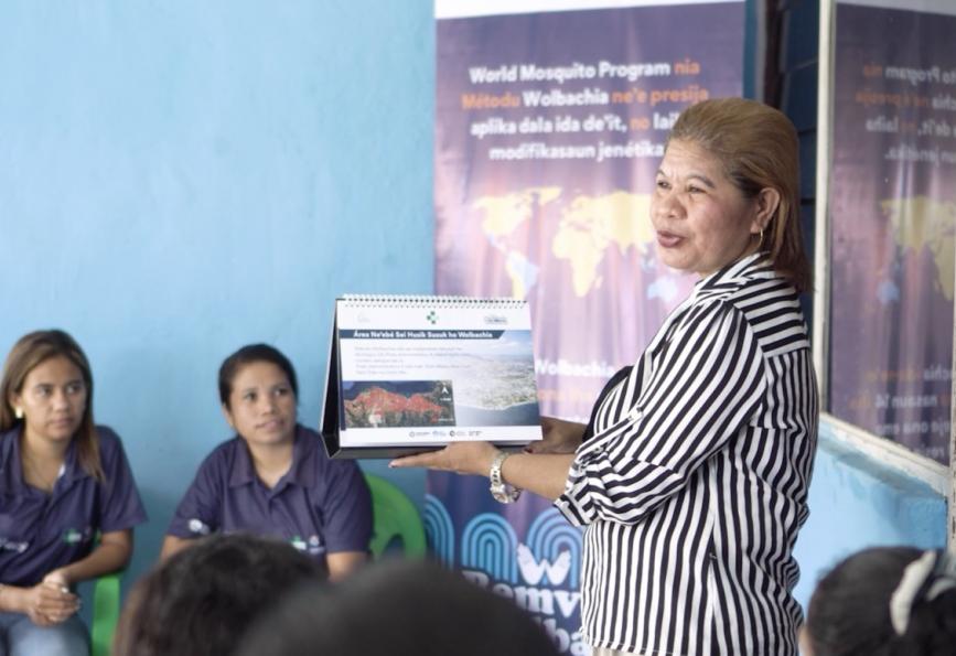 Foto de Afliana Soares conversando com um grupo de membros da comunidade em Timor-Leste 