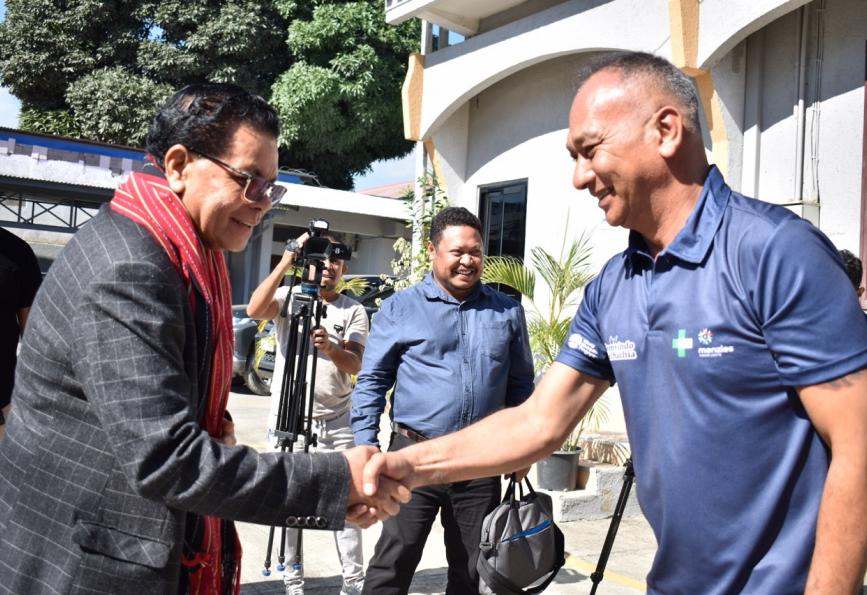 O Ministro da Saúde de Timor-Leste se encontra com um voluntário da organização “ World Mosquito Program ”. Câmera ao fundo. 